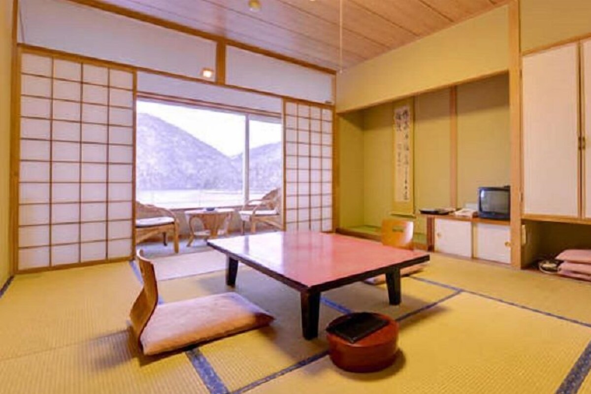 Una habitación japonesa tradicional con suelo de tatami, una mesa baja, un sofá y puertas correderas.
