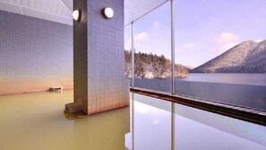 A spa area with a large window offering a view of a lake and mountains. - Shikaribetsu-kohan Onsen Hotel Fuusui (Shikaoi)