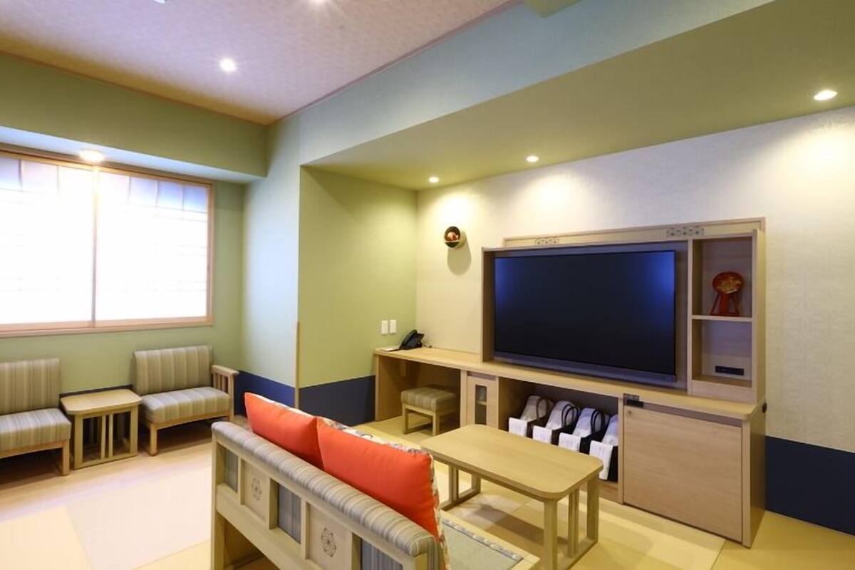 A living room with a television, seating, and a window.