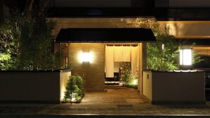 A modern house with a wooden entrance, a small garden, and a lit pathway leading to the door. - Dandan No Yu Onyado Nono Matsue (Matsue)