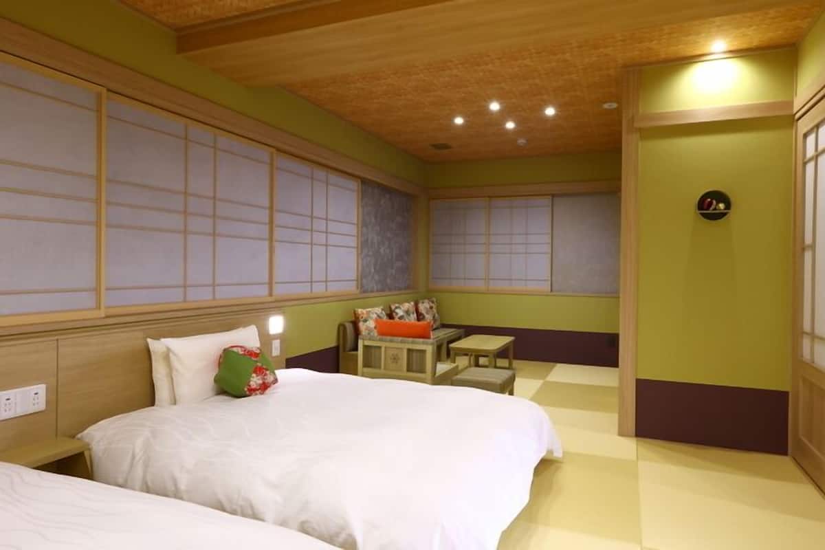 A hotel room with two beds, a small seating area, and a traditional Japanese-style sliding door.