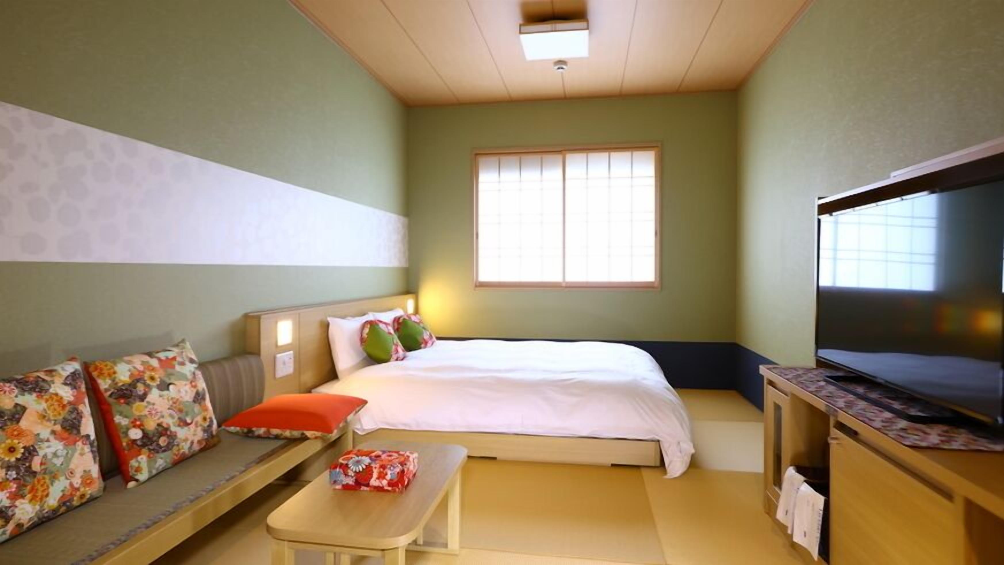 Ein Hotelzimmer mit Bett, einer Couch, einem Fernseher und einem kleinen Tisch.