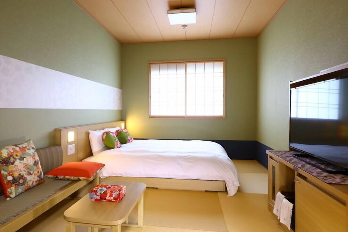 A hotel room with a bed, a sofa, a TV, and a small table.