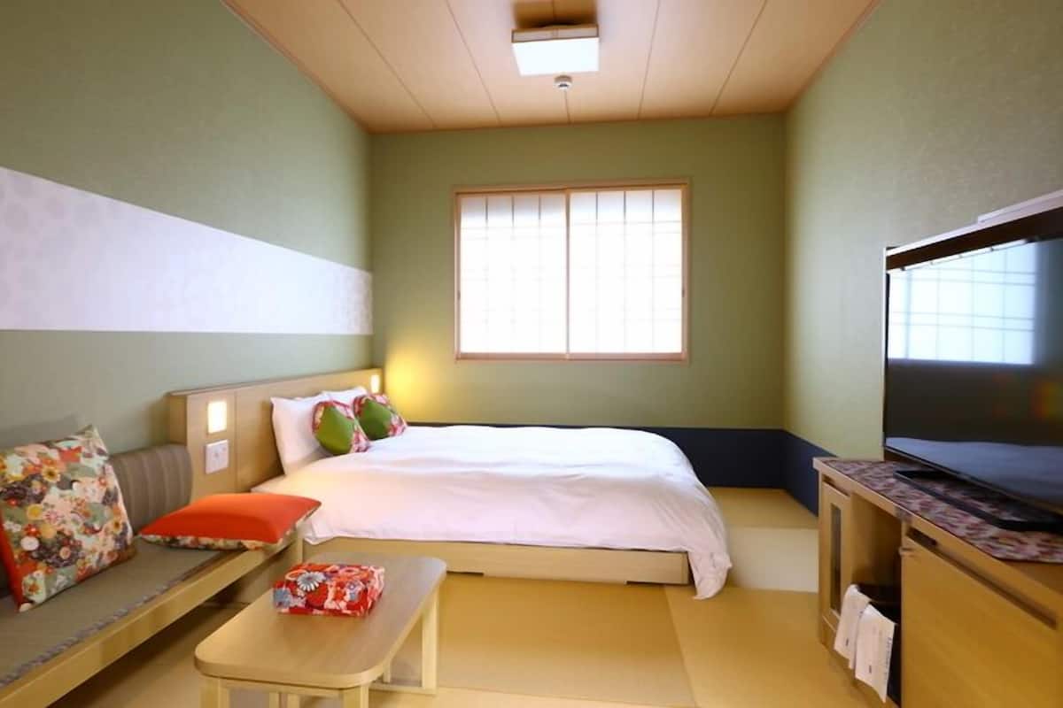 A hotel room with a bed, a sofa, a TV, and a small table.