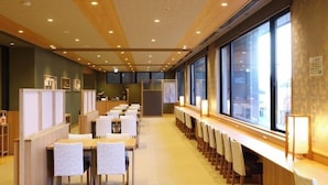 A long dining area with high tables and chairs, a counter with a cash register, and large windows along one wall. - Dandan No Yu Onyado Nono Matsue (Matsue)