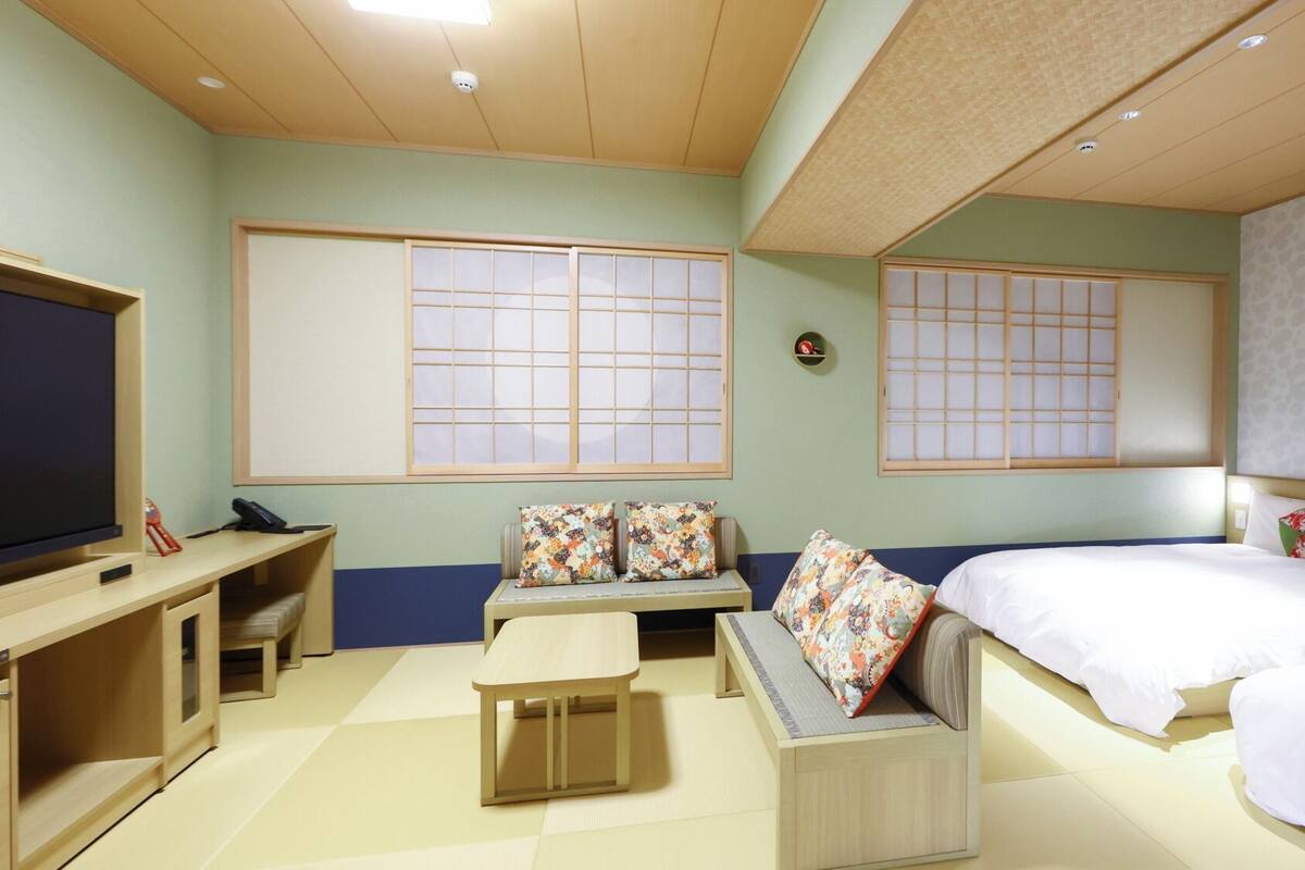 A hotel room with a bed, a sofa, a TV, and a desk.