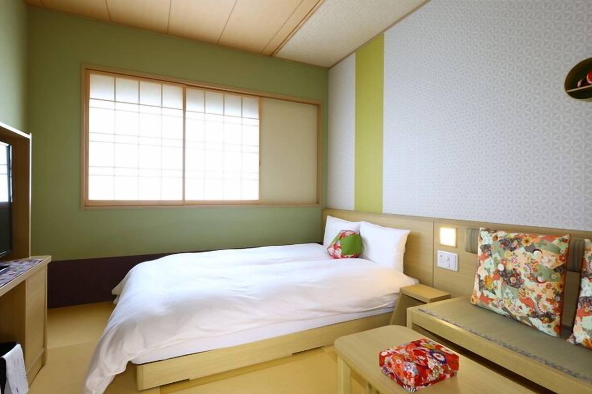 A room with a bed, a desk, a chair, and a window.