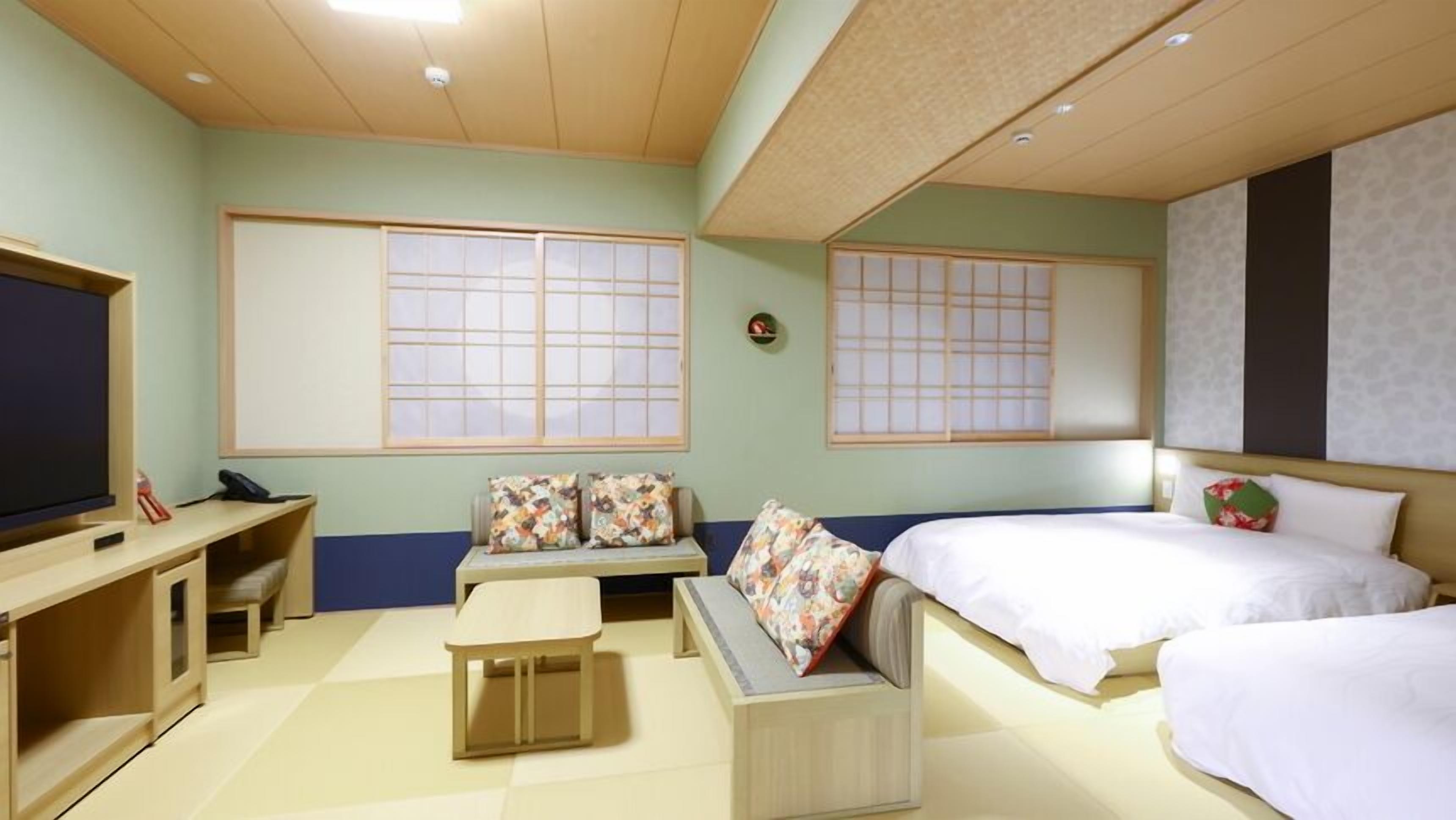 Ein Hotelzimmer mit Bett, Sofa, Fernseher und Schreibtisch.