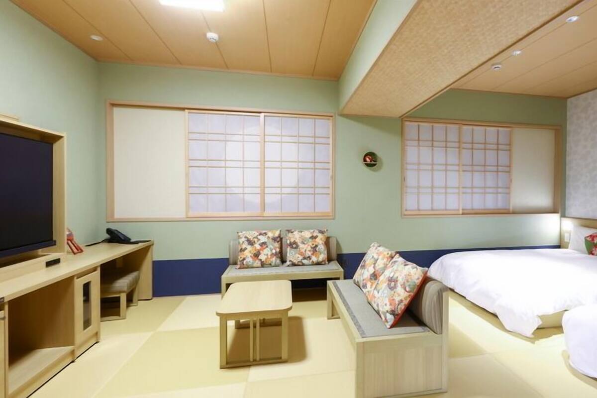 A hotel room with a bed, a sofa, a TV, and a desk.