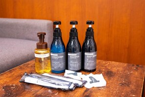 A wooden table with four bottles of personal care products and some packets on it. - Coco Shuku Nakano (Tokyo)