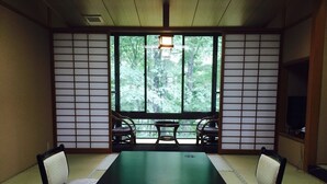 Um quarto japonês tradicional com piso de tatame, uma mesa baixa e portas deslizantes.