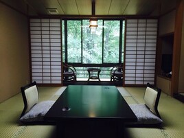 Una habitación japonesa tradicional con suelo de tatami, una mesa baja y puertas correderas.
