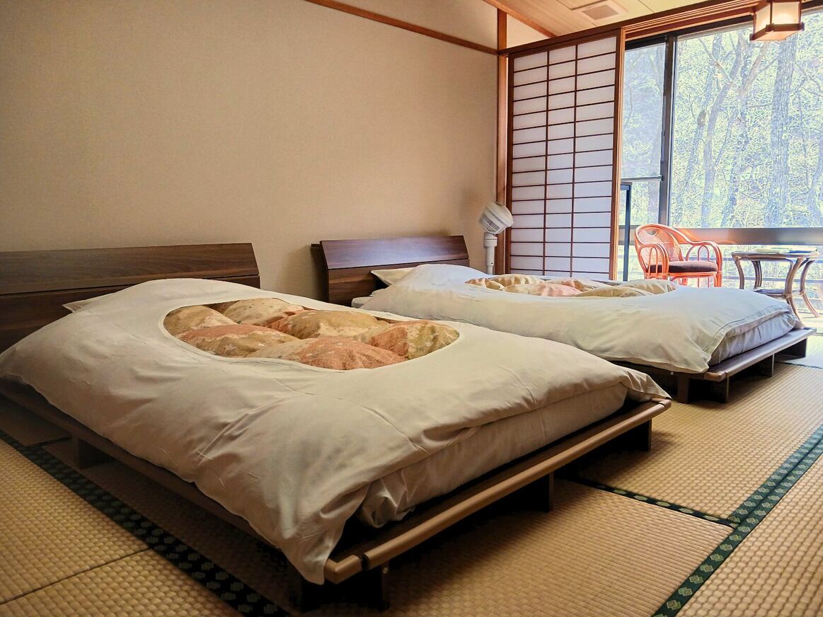 Two beds with tatami mats, a sliding door, and a view of trees.