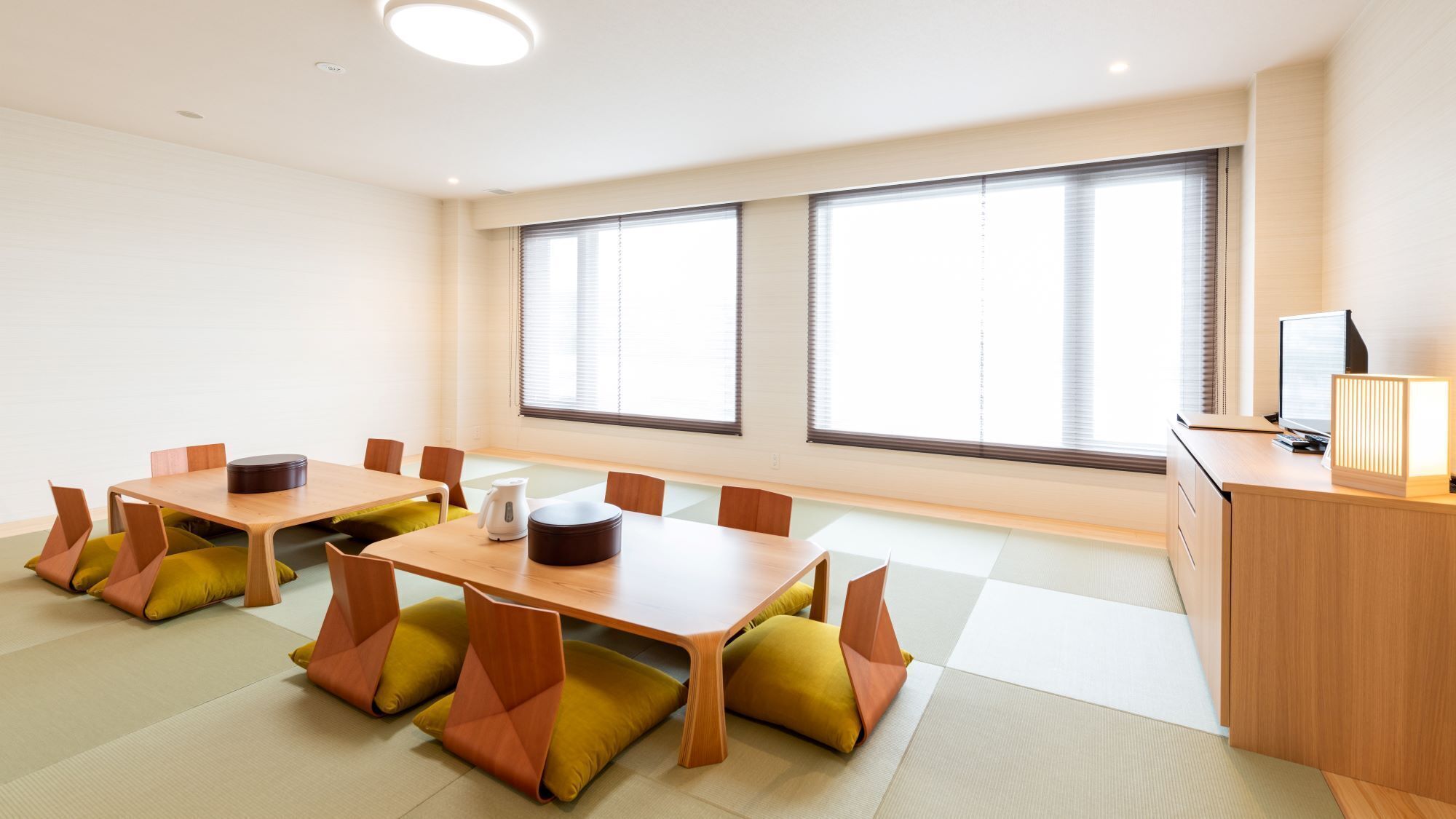 A modern meeting room with a wooden table, chairs, and a desk with a computer.