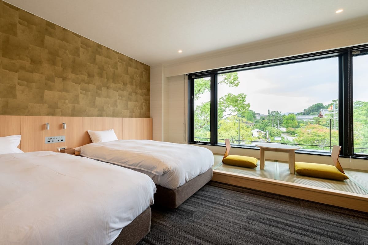 Ein modernes Hotelzimmer mit zwei Betten, einem großen Fenster mit Blick und einem kleinen Tisch.