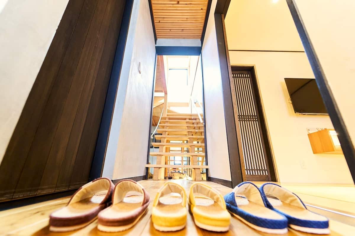 A staircase leading to a higher floor, wooden flooring, and a pair of slippers in front.
