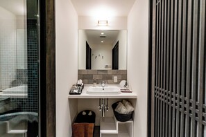 Ein modernes Badezimmer mit Waschbecken, Spiegel und einer gefliesten Rückwand.