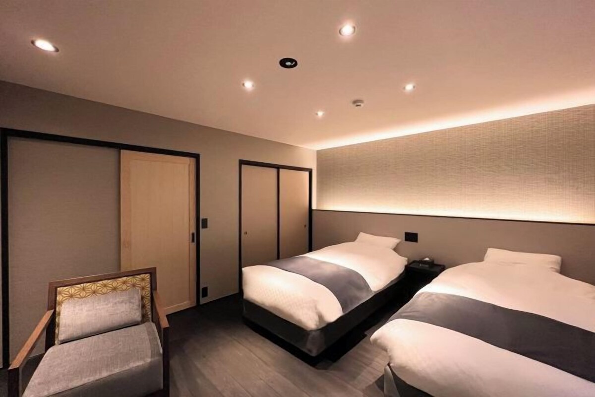 A hotel room with a bed, a chair, and a wardrobe.