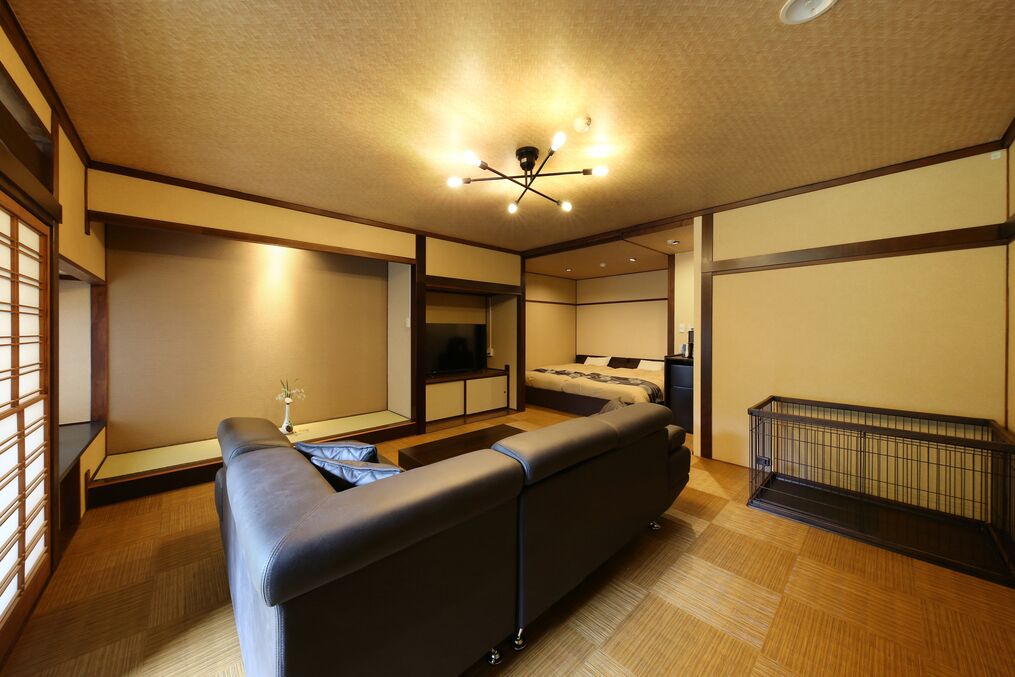Una habitación de hotel moderna con sofá, televisión, cama y una mesita.