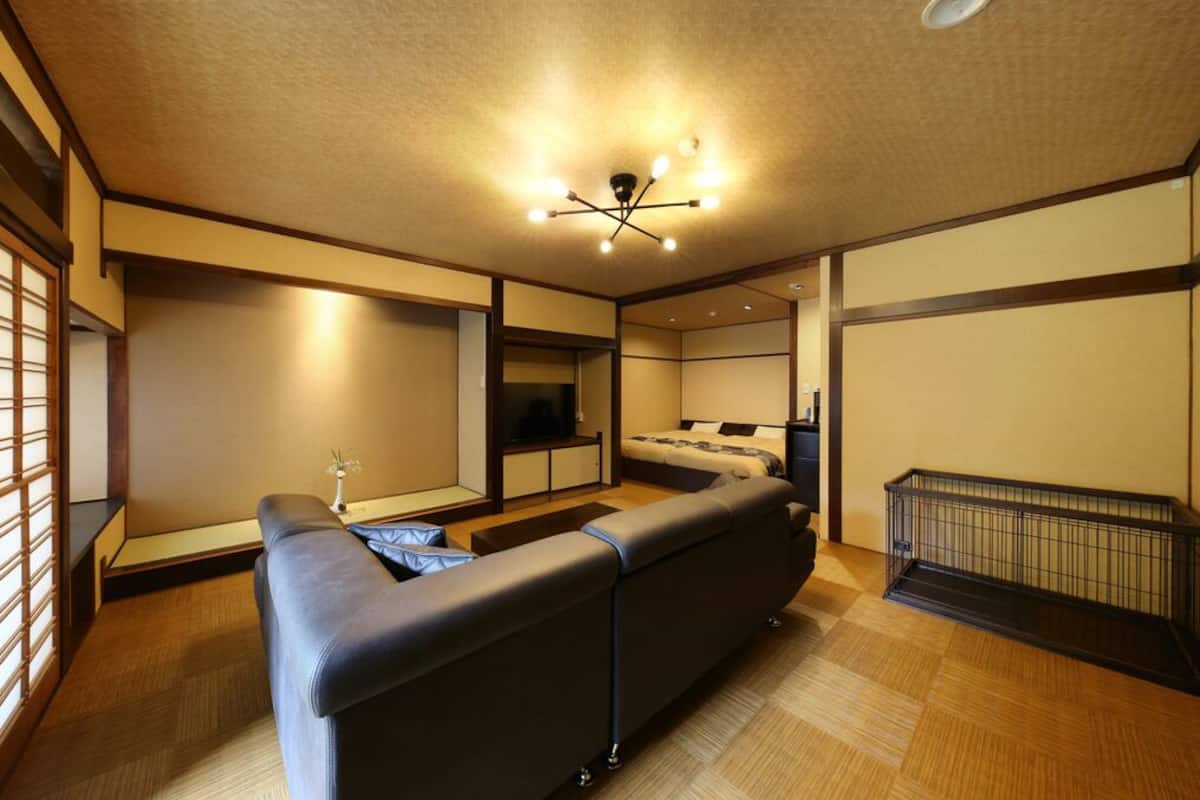 A modern hotel room with a sofa, a TV, a bed, and a small table.
