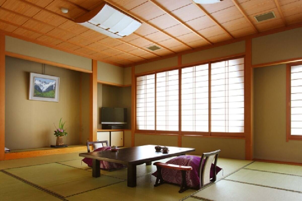 A traditional Japanese room with tatami flooring, a low table, a TV, and sliding doors.