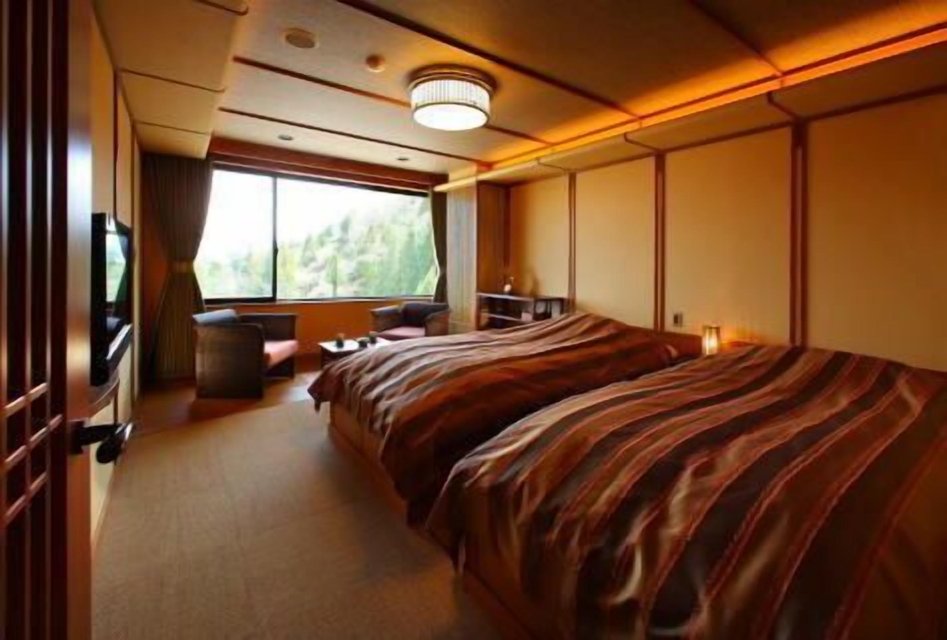 Una habitación con una cama, una mesita, una silla, un televisor y una ventana.