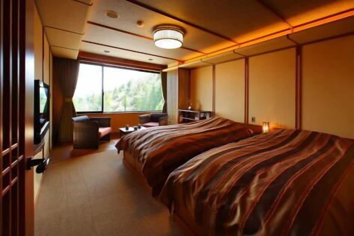 Una habitación con una cama, una mesita, una silla, un televisor y una ventana.