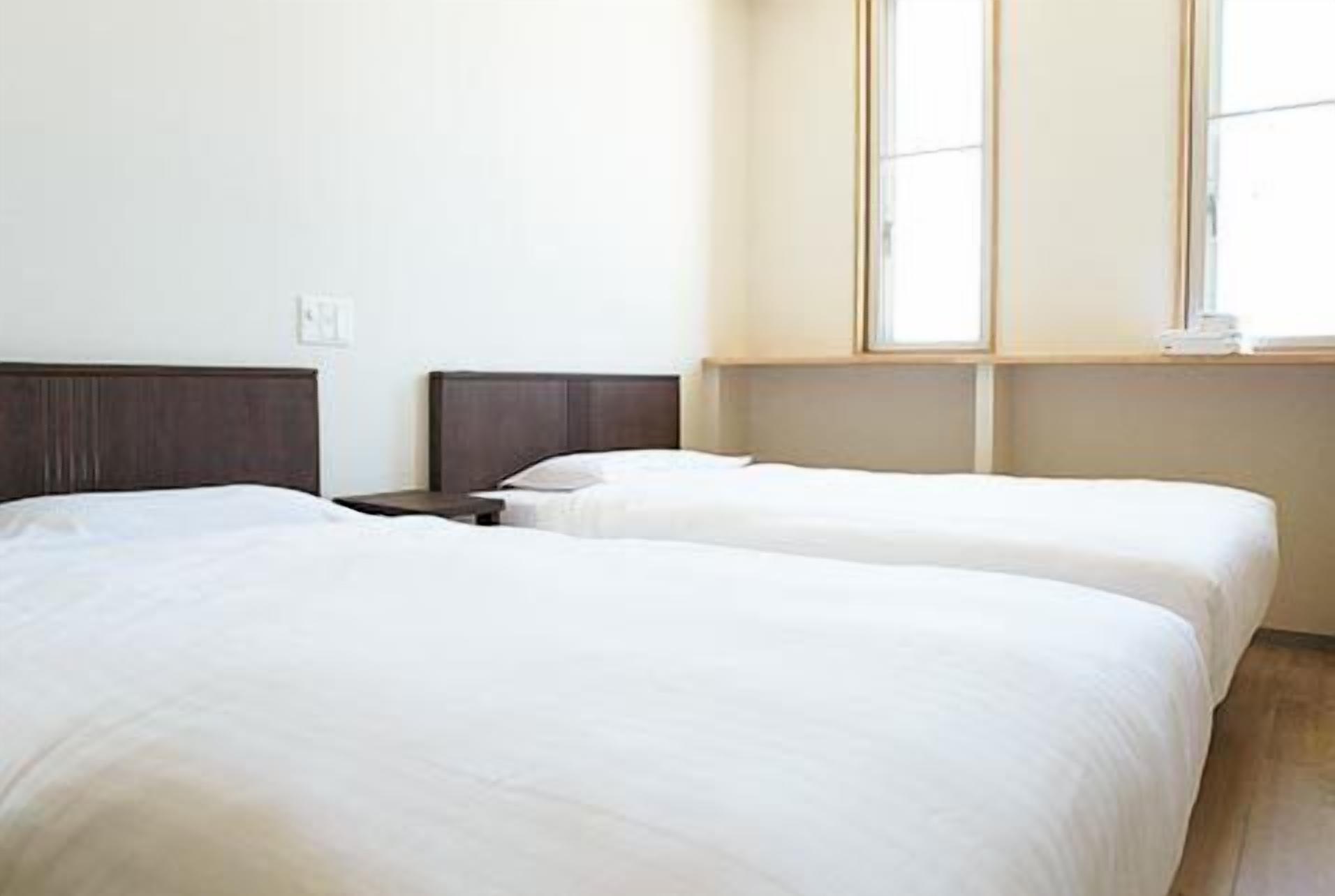 A hotel room with two beds, a window, and a nightstand.