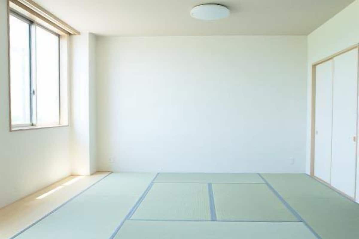 Una habitación con esteras de tatami, una ventana y una puerta.