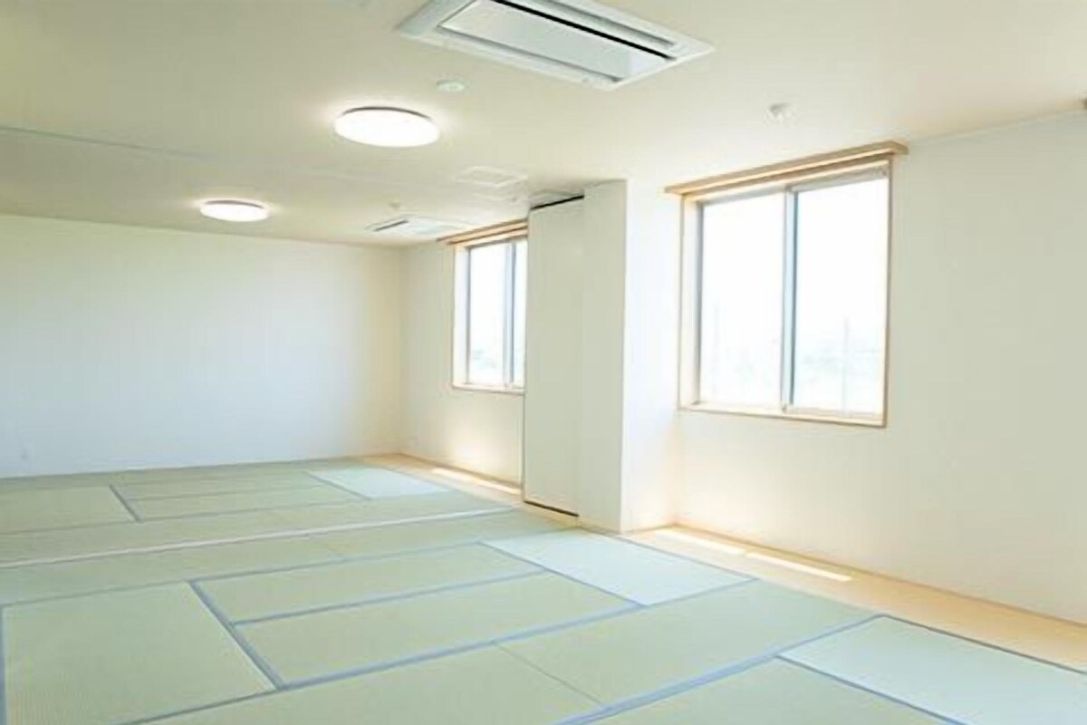 Una habitación con esteras de tatami, una puerta corredera y una ventana.