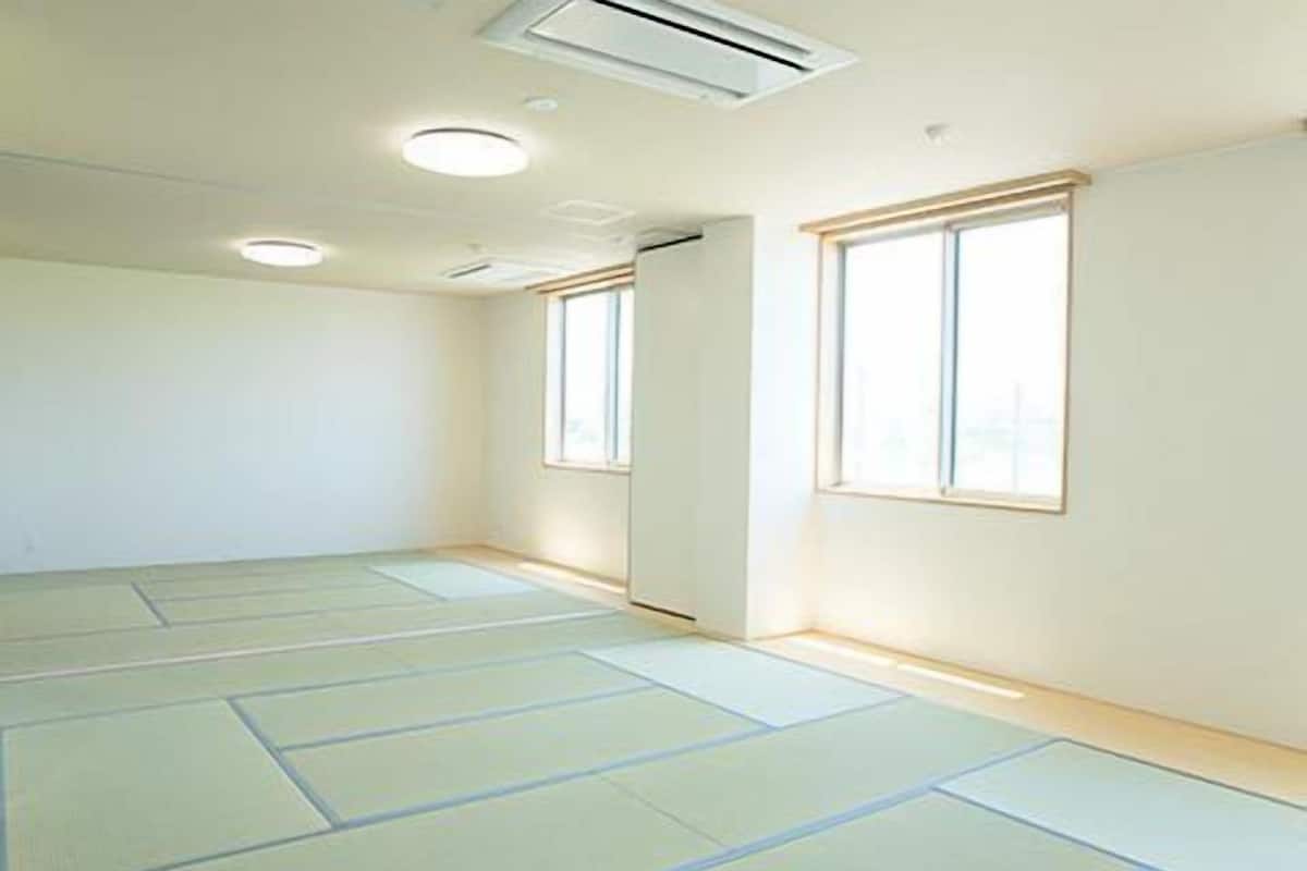 Una habitación con esteras de tatami, un respiradero en el techo y una ventana.