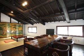 Ett traditionellt japanskt rum med tatamimattor på golvet, ett lågt träbord och en stor tavla på väggen.