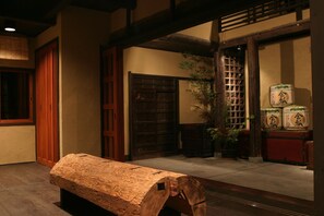 Ett traditionellt japanskt rum med tatamimattor på golvet, en träbänk, skjutdörrar och en krukväxt.