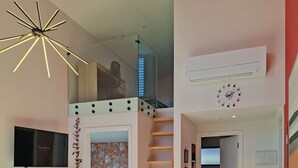 Un espace de vie moderne comprenant un escalier, un coin repas, un canapé et un téléviseur.