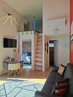 A modern living space with a staircase, a dining area, a sofa, and a TV. - Modern Wanaka Escape with Mezzanine Loft (Wānaka)