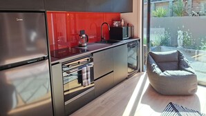 Une cuisine moderne dotée d’un réfrigérateur en acier inoxydable, d’un crédence rouge et d’un lave-vaisselle encastré.