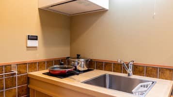 A compact kitchen with a sink, a stove, and a range hood.