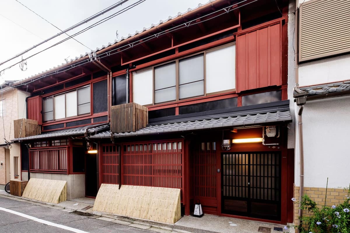 Un edificio tradicional japonés con fachada roja, grandes puertas correderas y tejado de tejas.