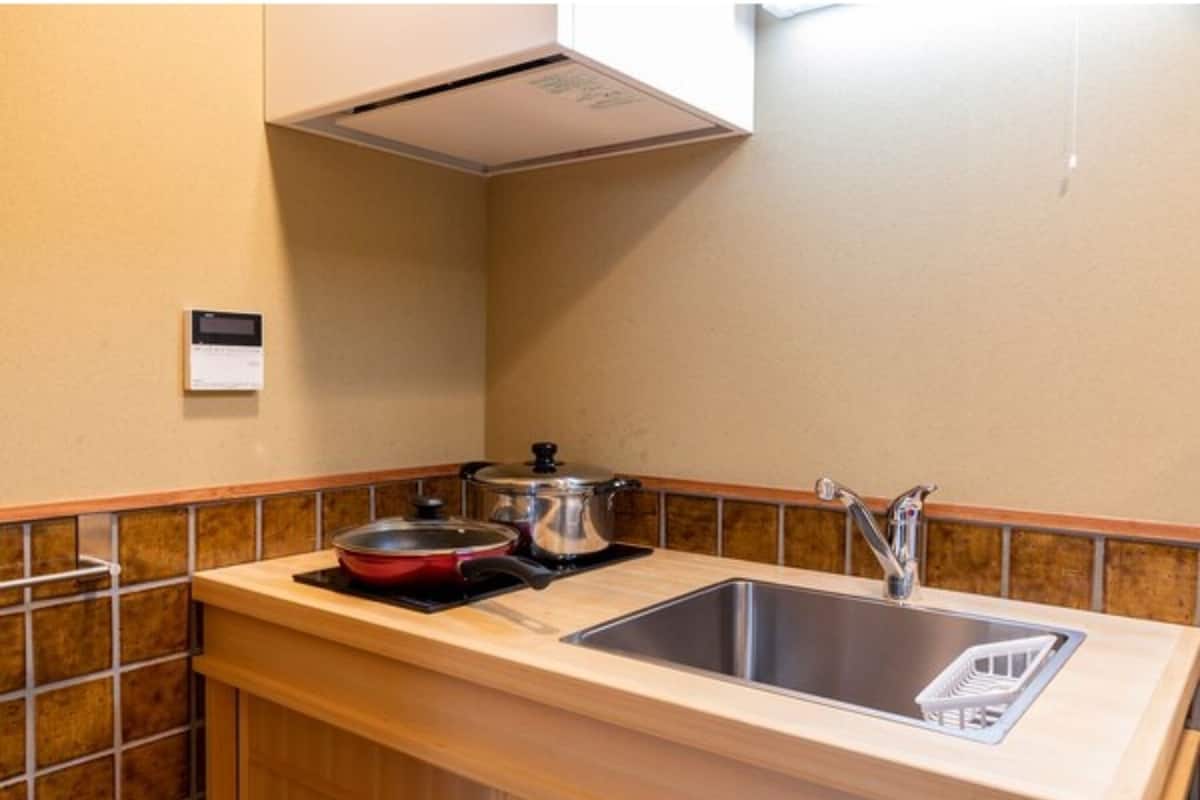 Una cocina con un lavamanos, estufa y un termostato instalado en la pared.