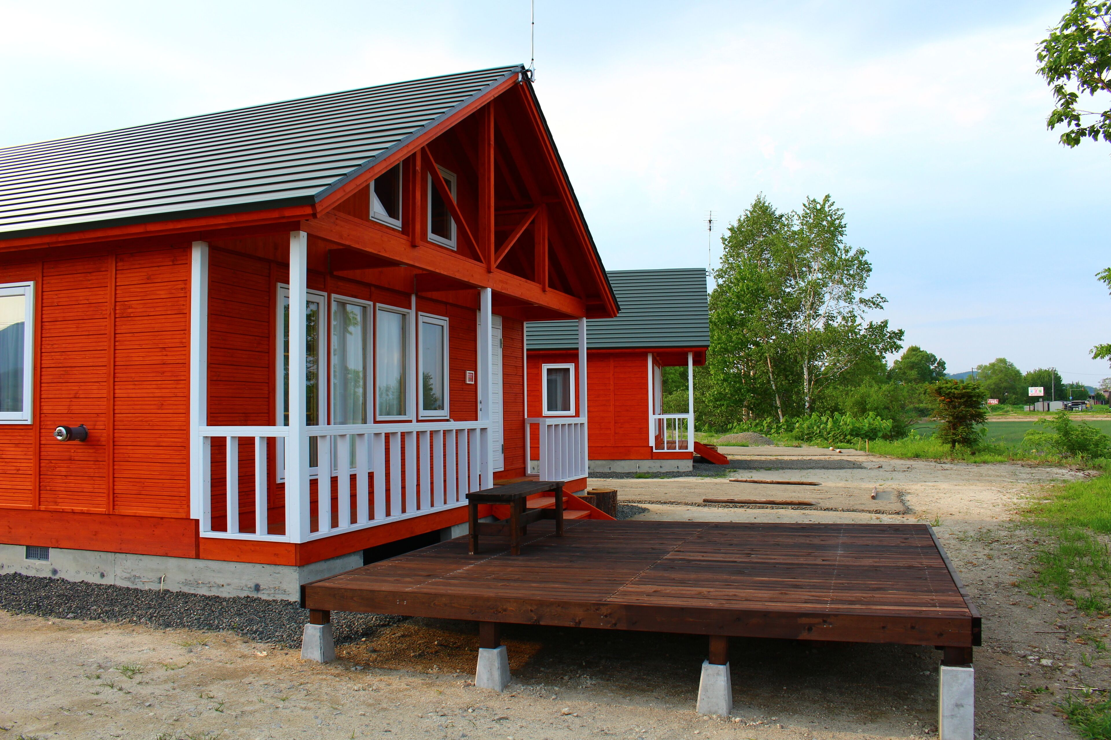 A red building with a porch and a wooden deck.
