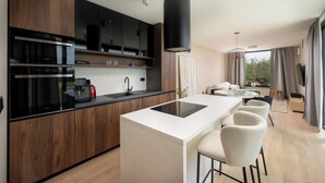 Una cocina moderna con una isla central, electrodomésticos integrados y un comedor con una mesa redonda y sillas.