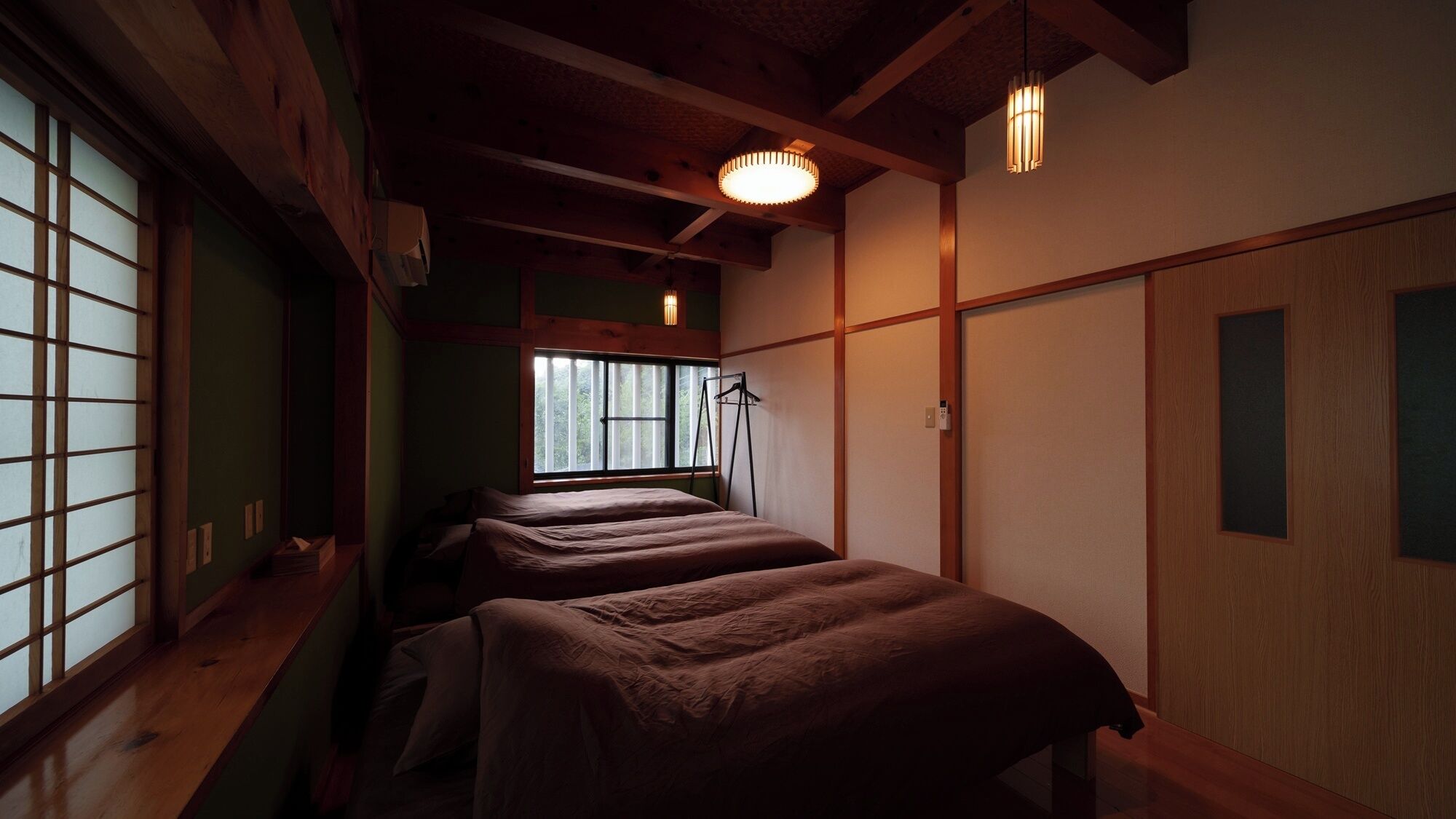 A traditional Japanese room with tatami flooring, a sliding door, and a bed with a futon.