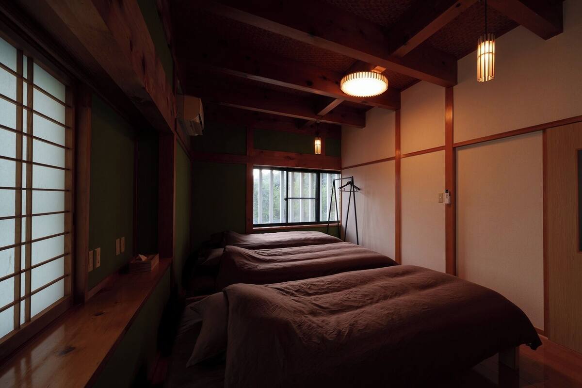 A traditional Japanese room with tatami flooring, a sliding door, and a bed with a futon.
