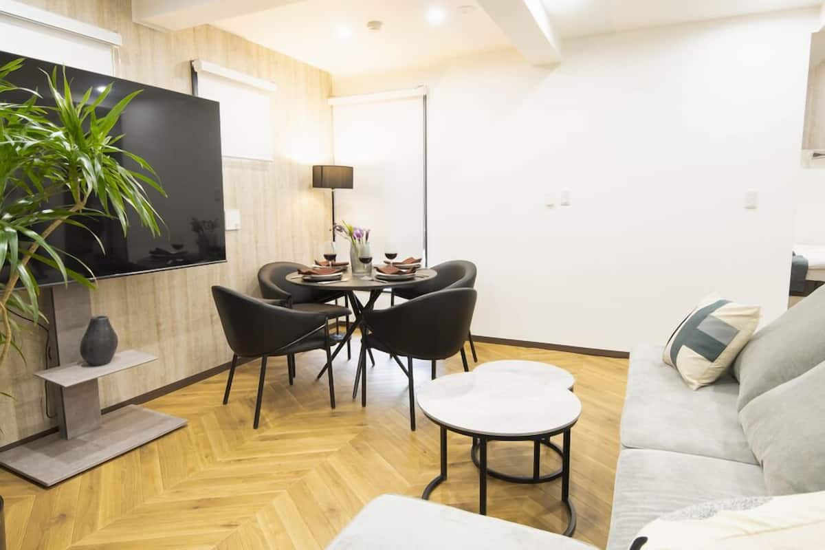 Un salon moderne avec un téléviseur à écran plat, une table à manger avec des chaises, un canapé et une plante en pot.