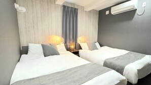 A hotel room with two beds, a window with curtains, a wall-mounted air conditioner, and bedside lamps. - Grandioso Urban Stay Shinjuku East (Tokyo)