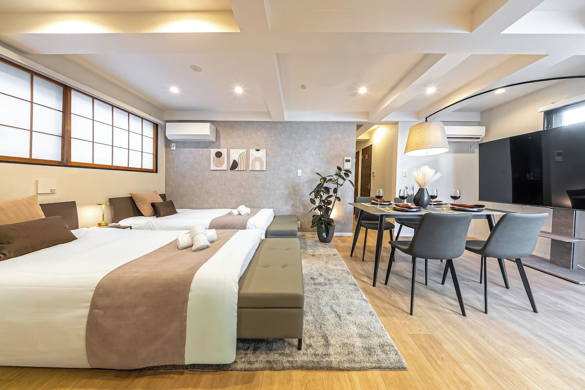 Une chambre d’hôtel moderne avec deux lits, un coin repas et une télévision.