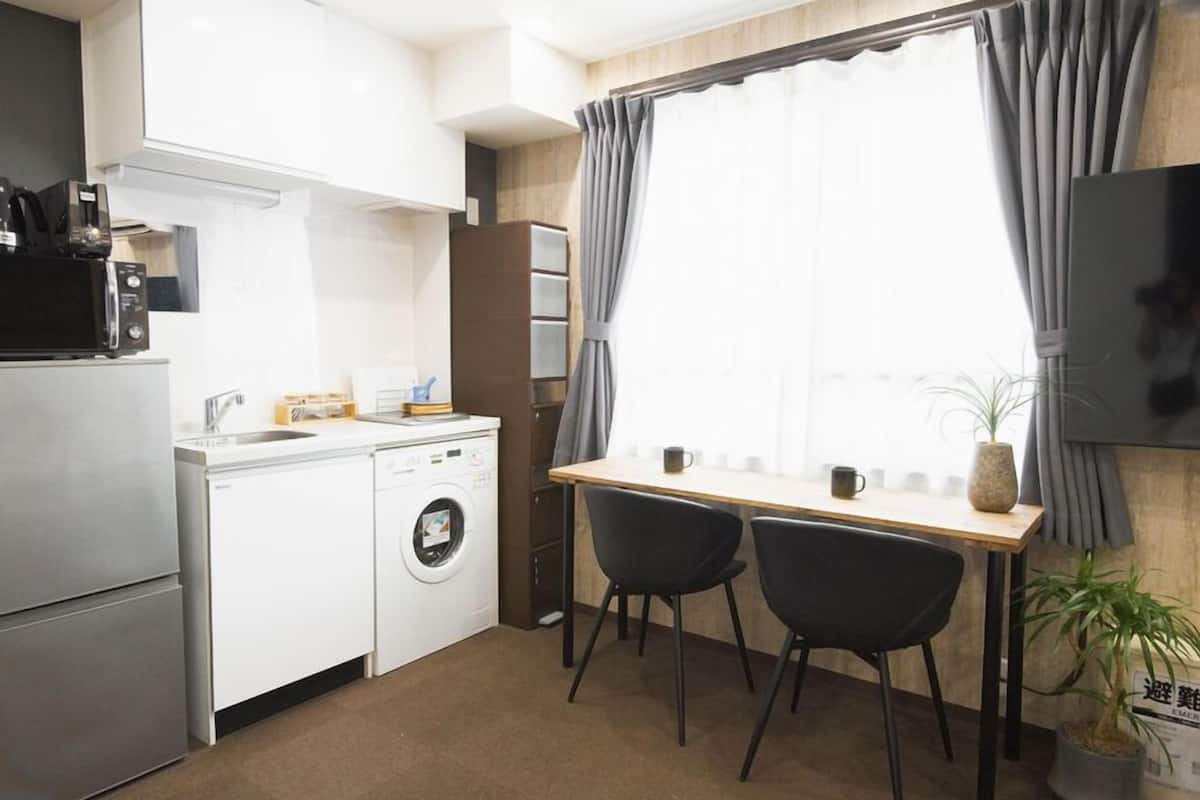 Une cuisine compacte  équipée d’un lave-linge, d’un four à micro-ondes et d’un petit coin repas avec deux chaises.
