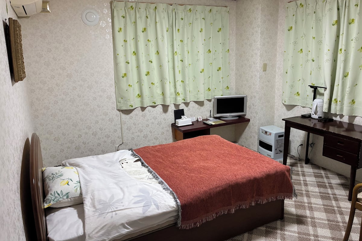 Un dormitorio con una cama, un escritorio, una computadora y una cafetera.