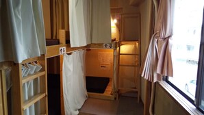 A narrow corridor with bunk beds, a ladder, and a window with curtains. - Moritomizu Backpackers (Nagano)