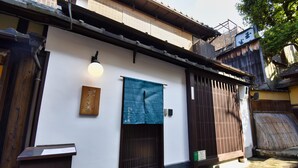 A traditional Japanese building with a wooden gate, a blue hanging cloth, and a white wall. - Kyo no Katadomari Kiyomizu Birodo-an (Kyoto)